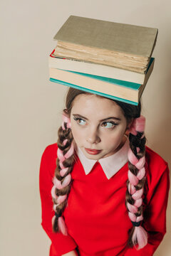 Woman balancing books on head near wall