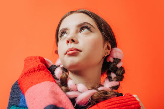 Woman wearing multi colored sweater against red background