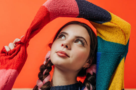 Smiling woman wearing multi colored sweater against red background