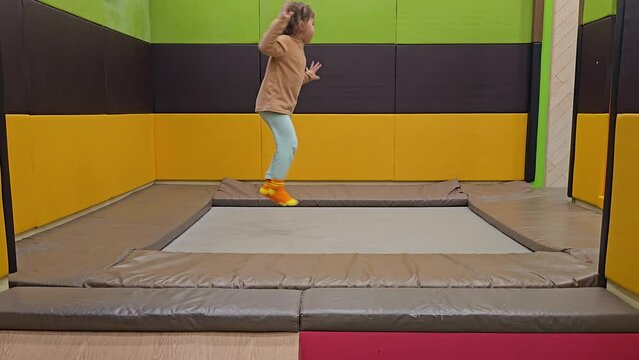 Active child girl jumps on a trampoline alone