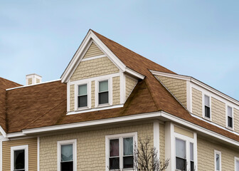 Dormer windows on the sloped shingle roof of a newly built house in Brighton, MA, USA
