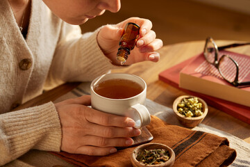 Woman add essential oil to her herbal infusion drink