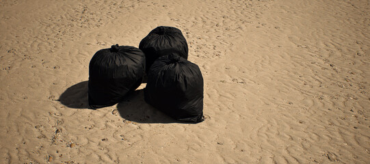 Three black trash bags left on tropical beach with rippled sand. - 746437030