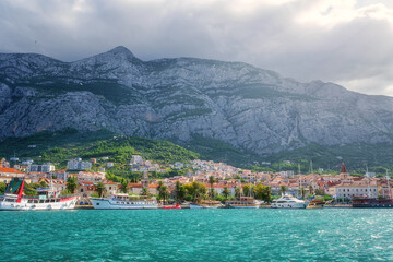 Scenic view of the harbor and old town of Makarska, Dalmatia, Croatia. Summer landscape with yachts, sea, architecture and rocks, famous tourist destination at Adriatic seacoast, travel background
