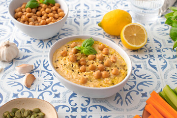 A comforting bowl of hummus with carrots, celery, pumpkin seeds, and garlic