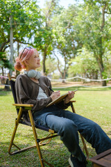 Fototapeta premium Woman among nature wearing glasses and head phone reading a book.