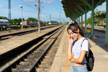 Young Asian woman enjoy and fun outdoor lifestyle road trip travel by railway transportation on summer holiday vacation. Attractive girl walking on railroad track during waiting for train at station.