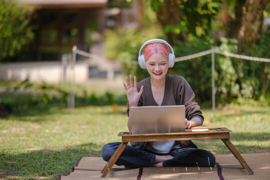 Shot of casual young woman sitting in the garden and using laptop.