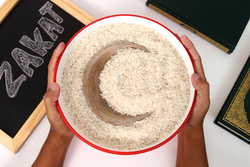 Hand holding a bowl of rice with a crescent moon shape in the center representing Ramadan Kareem...