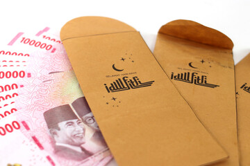 Close-up view THR envelope filled with Indonesian Rupiah banknotes. THR or Tunjangan Hari Raya is a holiday allowance or bonus traditionally given to employees and those in need near during Ramadan