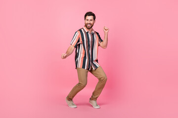 Fototapeta na wymiar Full length size photo of funny brunet positive man dancing wear striped shirt brown pants sneakers isolated on pink color background