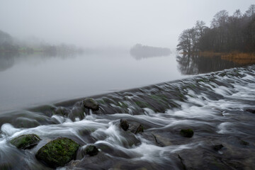 Flowing water at Grasmere weir on a misty morning in The Lake District, UK. - 746455617