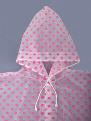Close-up fragment of a pink polka dot raincoat with laces? cape and buttons.  Waterproof clothing ...