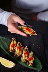 mussel with red caviar in hand on a black wooden background