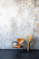 A leather chair on wood flooring contrasts against a concrete wall