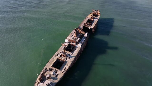 Flight over the shipwreck. 4K Aerial drone shot. A lone old ship wreck in the middle of the sea. Birds fly around the ship.