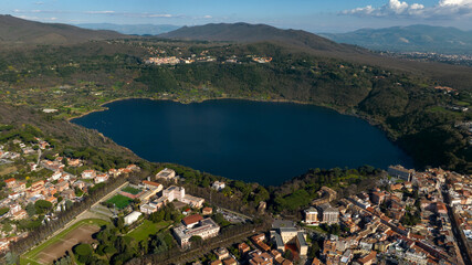 Aerial view of Lake Nemi. It is a small volcanic lake in the territory of the Castelli Romani. In foreground it is Genzano di Roma, a small town located in the Metropolitan City of Rome, Italy. 