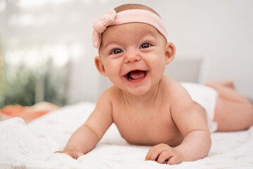 Close-up portrait of a laughing baby with his mouth open lying on a blanket. Concept of learning and development in childhood. educate positively. secure attachment. respectful parenting