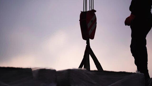  Construction crane hook at work. Lifting hook․ Crane lifts a load with a hook․ Worker near crane cook. Construction works in evening time.