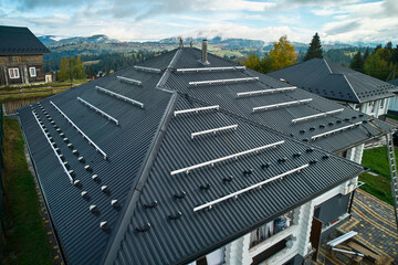 Preparing for installation on roof of wooden house in mountains. Solar panels securing. Modern and...