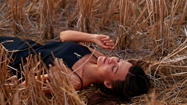 Young playful woman lying on the straw field