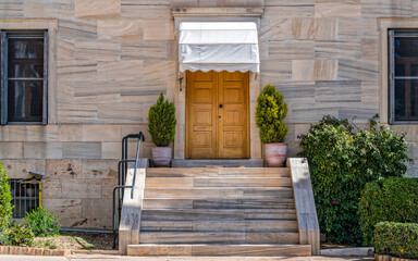 A classic marble covered building facade and stairs to a solid natural wood door. Travel to Athens,...