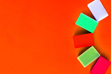 Multicolor sponges for washing dishes on orange background. Minimal concept. Copy space for the text