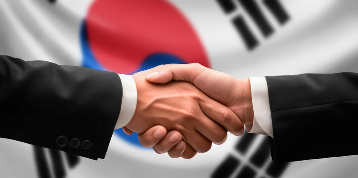 Businessman, diplomat in suits clasp hands for handshake over South Korea flag, agree on united success in trade, diplomacy, cooperation, negotiation, teamwork in commerce, gesture of greeting