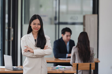 Fototapeta premium Portrait of beautiful businesswoman standing in the office room with her team in the background.