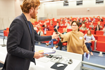 Orator giving microphone to audience in business conference
