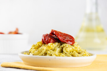 Pasta Creste Di Gallo with sun-dried tomatoes and pesto sauce in a plate. Rooster scallop.