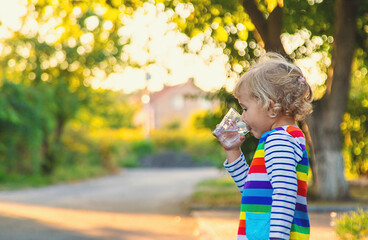 a child drinks water from a glass. Selective focus.