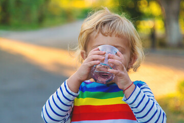 a child drinks water from a glass. Selective focus.