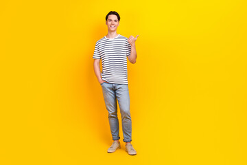 Fototapeta na wymiar Full size photo of preppy student dressed striped t-shirt jeans trousers directing at sale empty space isolated on yellow color background