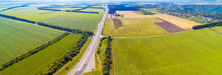 Sunny day in the countryside. Rural landscape in daylight. Aerial view of the highway among the fields. Horizontal banner