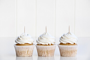 Three Vanilla Cupcakes Topper Mockup. 3 cupcake with wooden toothpick in white background Copy space for your design here. Blank mockup for advertising and promotions - obrazy, fototapety, plakaty