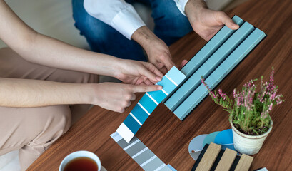Interior designer and customer choosing home design materials from acoustic panel samples in the...