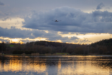 Samolot lecący nad zbiornikiem wodnym / jeziorem na tle zachodzącego słońca | The flying plane...