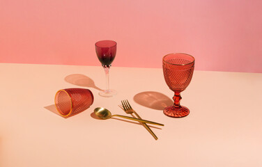 Arrangement of red  wine glasses and gold cutlery. Minimal concept  fork, spun and glasses on beige...