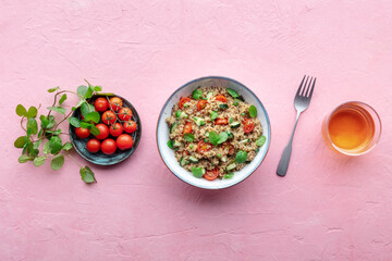 Quinoa tabbouleh salad in a bowl, a healthy dinner with tomatoes and mint, with a drink, overhead...
