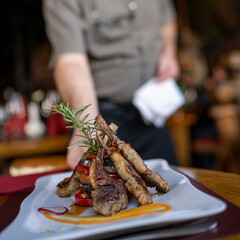 Grilled lamb chops tower over a medley of vegetables, artistically plated with herb garnish and...