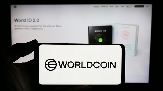 Stuttgart, Germany - 02-15-2024: Person holding smartphone with logo of cryptocurrency project Worldcoin (Tools for Humanity) in front of website. Focus on phone display.