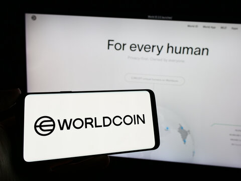 Stuttgart, Germany - 02-15-2024: Person holding cellphone with logo of cryptocurrency project Worldcoin (Tools for Humanity) in front of business webpage. Focus on phone display.