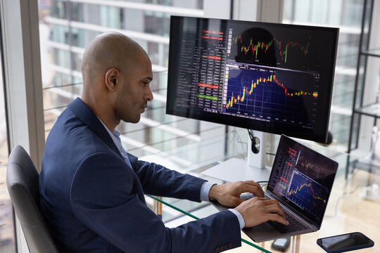 Stock trader looking at stocks and shares on computer in a high rise office