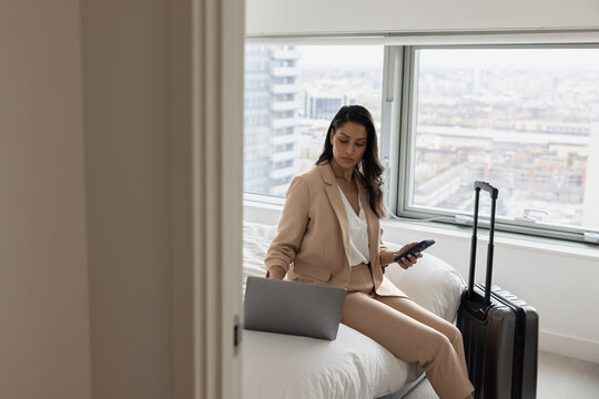 Business executive in hotel working using her cell phone