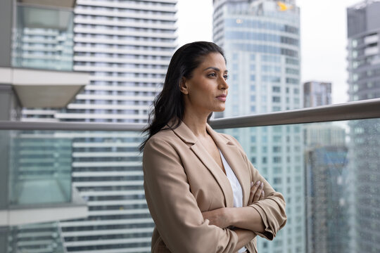 Businesswoman on office balcony looking confidently at city skyline