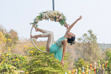 Beautiful Asian woman playing Rig and Hang Aerial Hook for Yoga in Nature scenery.