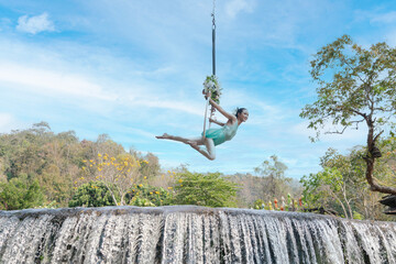 Beautiful Asian woman playing Rig and Hang Aerial Hook for Yoga in Nature scenery.