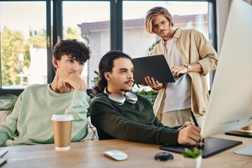 creative post production team of young men focused on a retouching project in a well-lit office