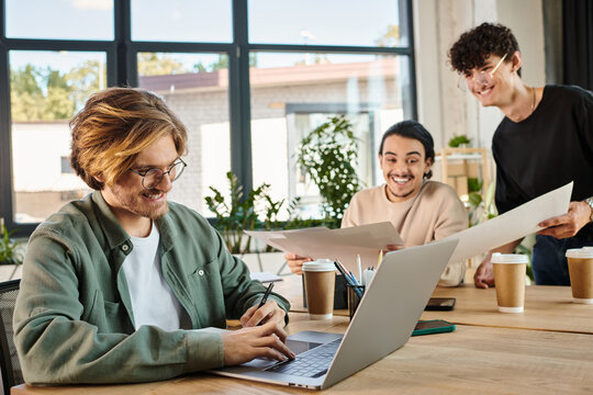 happy man using laptop, team of young entrepreneurs engaged in project planning in office